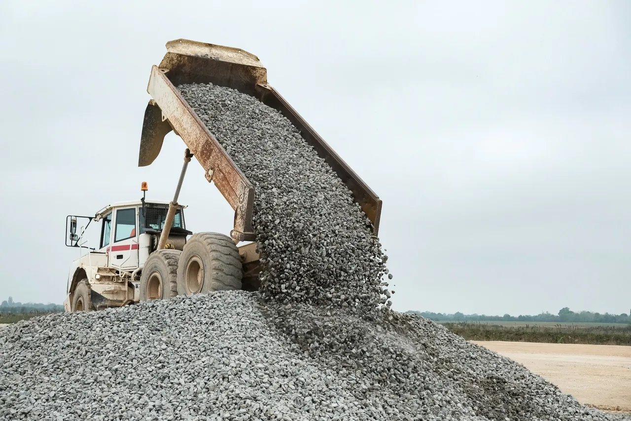 Camion benne déchargeant du gravier sur un chantier