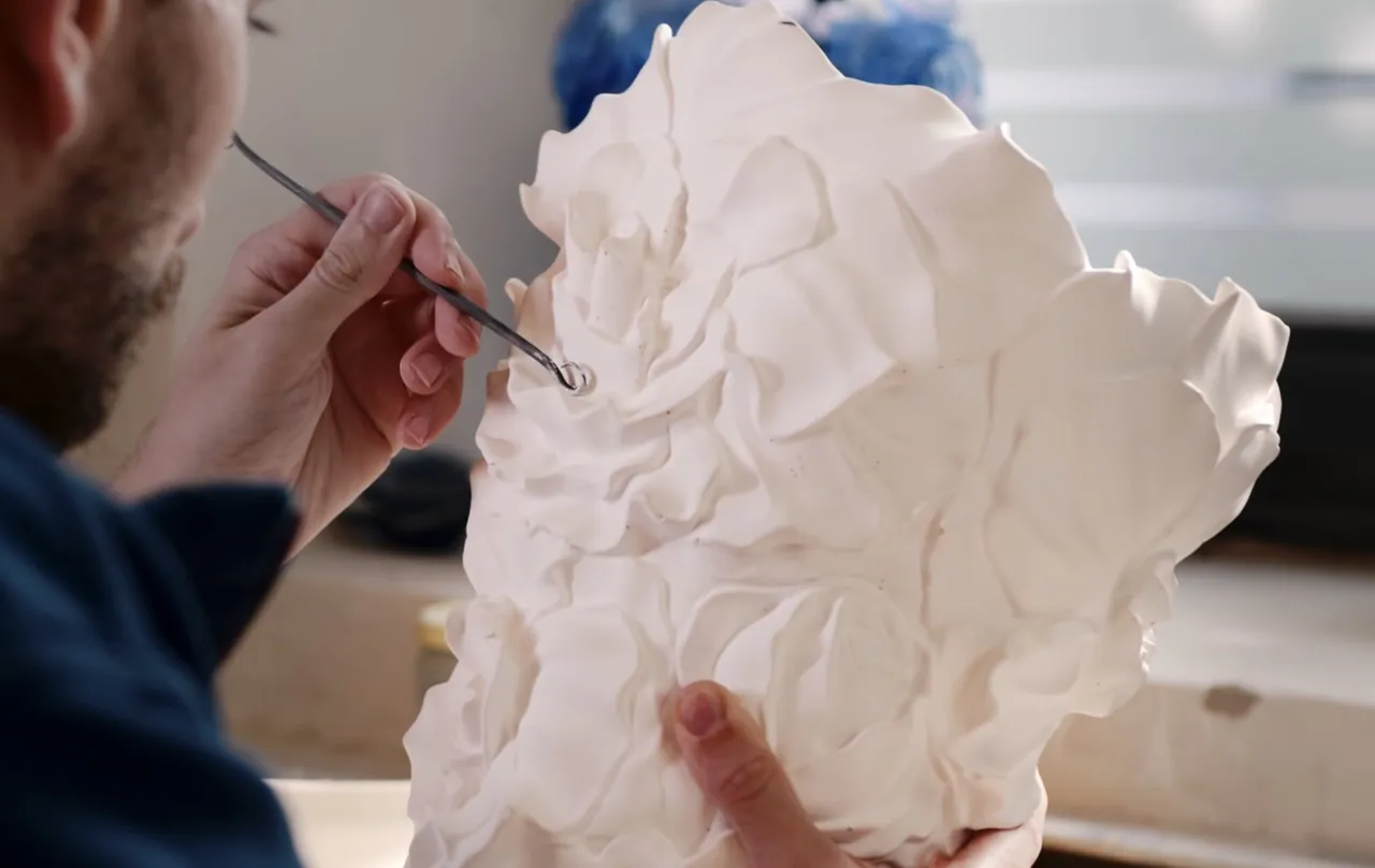 Main façonnant une fleur en porcelaine au pinceau